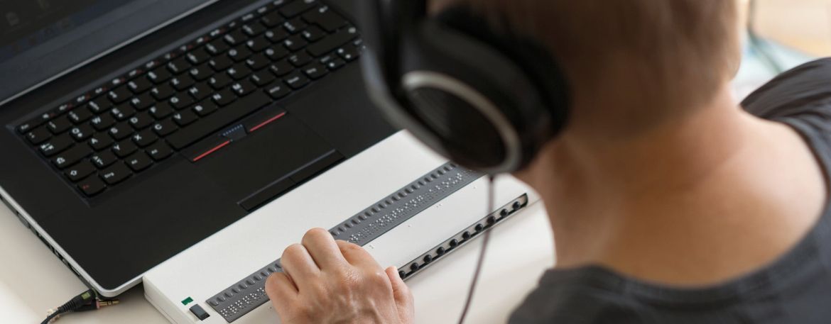 A person wearing heaphones looking at a laptop screen