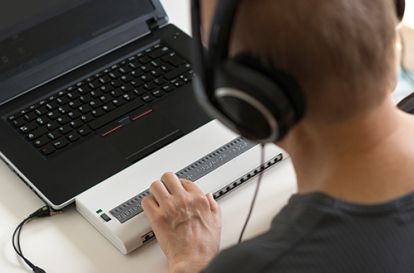 A person wearing heaphones looking at a laptop screen